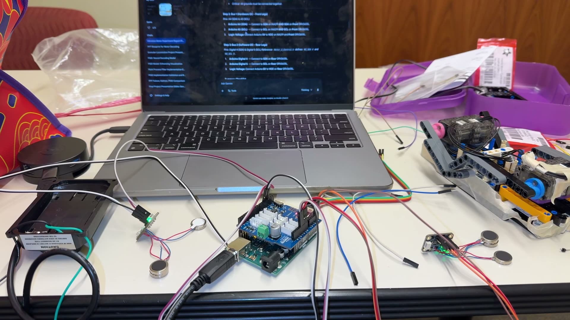 The vibration rig mid-build — Arduino, driver shield, coin motors, wiring doc on the laptop